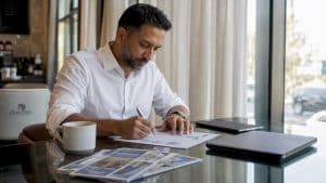 Man reviewing currency exchange documents at home